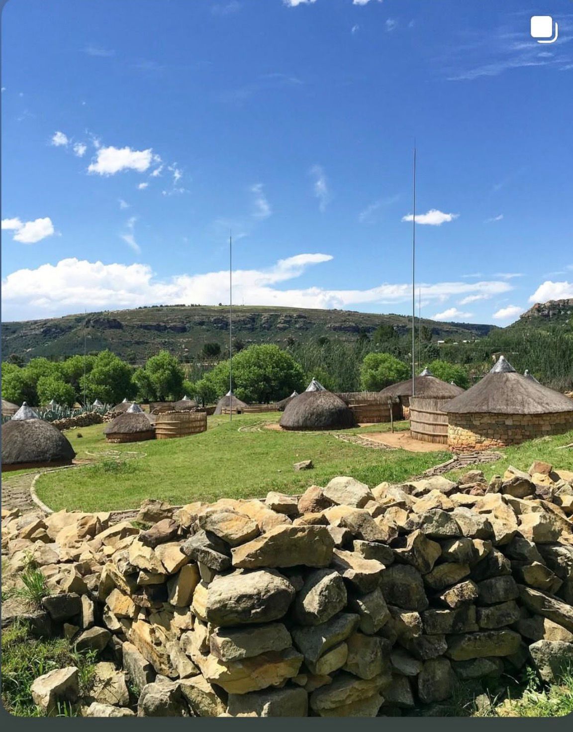 Stone walls and thatched huts with mountain backdrop